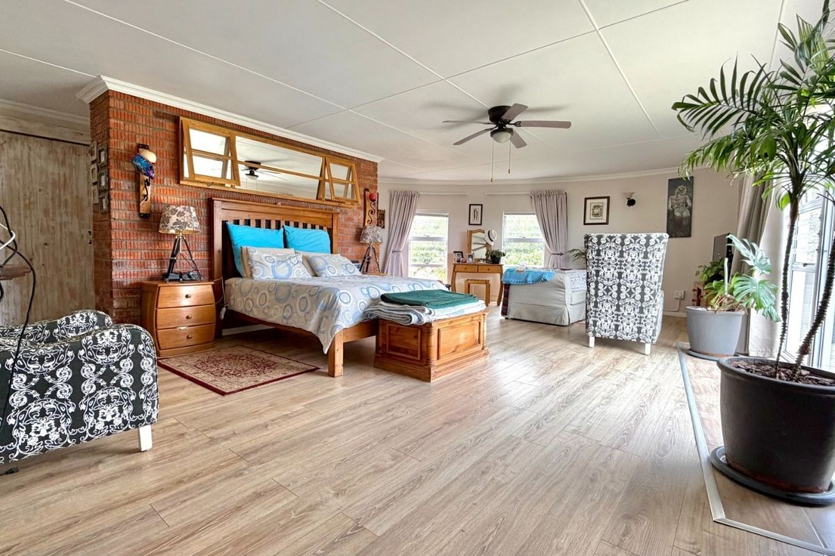 Spacious bedroom featuring exposed brick wall detailing, laminate flooring, a ceiling fan, and direct access to the outdoors via a sliding glass door.