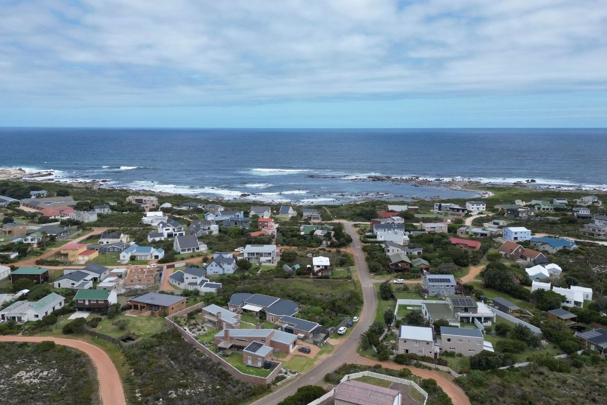An aerial view of a coastal residential neighborhood situated along the shoreline, showcasing the proximity to the ocean and surrounding landscape.