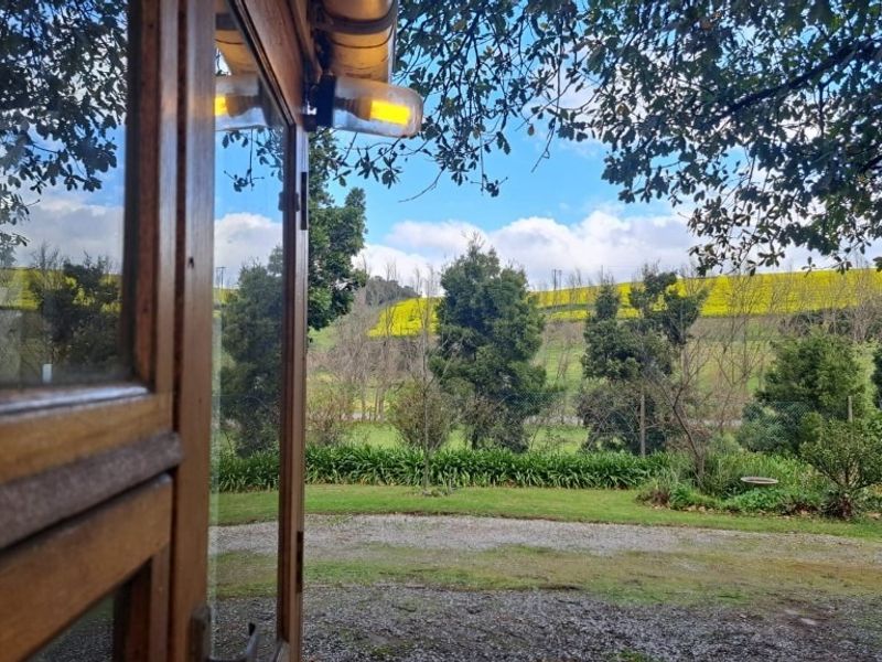 A scenic view of the farm landscape and rolling hills, framed by a timber window structure and exterior lighting.