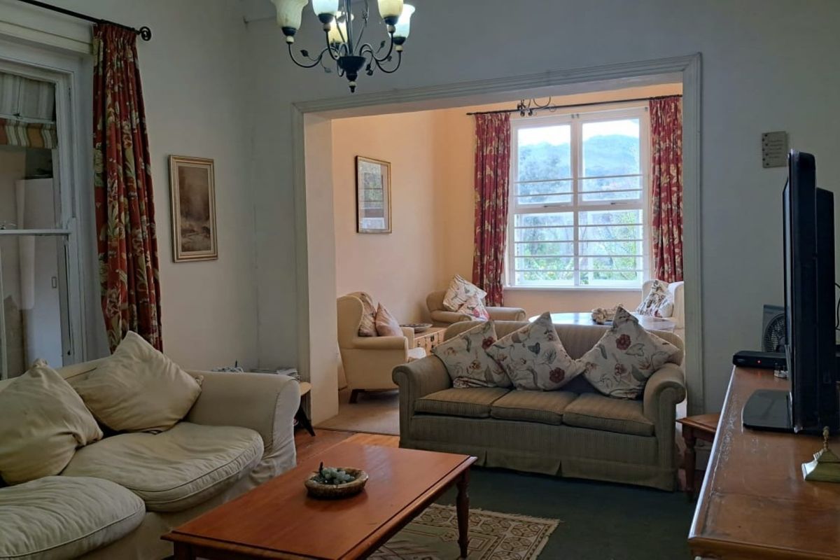 A spacious living area featuring classic sash windows, timber flooring, and a traditional chandelier, offering a comfortable and well-lit space.