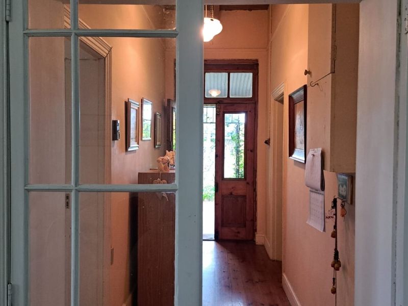 A traditional hallway featuring timber flooring and a glass-panelled entrance door, providing a warm and welcoming transition between living spaces.