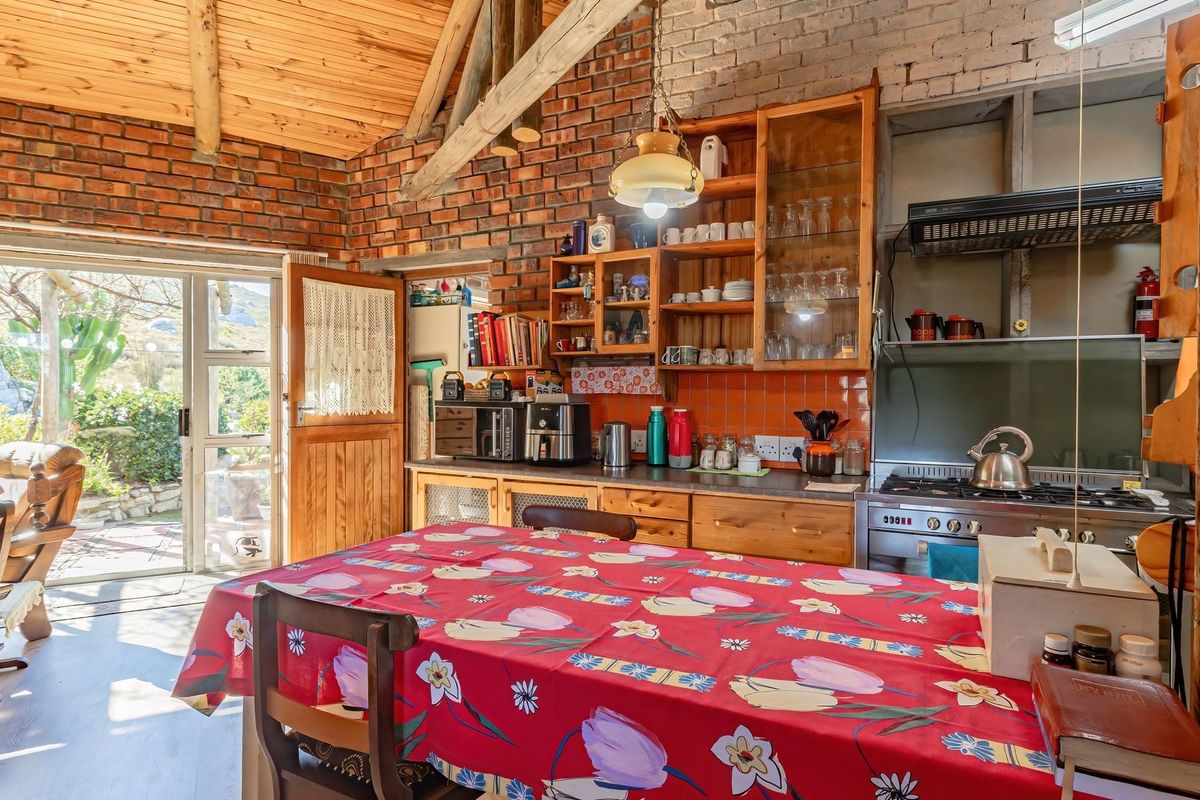 Rustic kitchen featuring exposed brick walls, timber vaulted ceilings, and built-in wooden cabinetry, with direct access to an outdoor patio area.