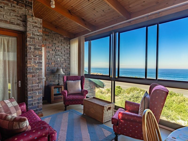Enclosed patio area featuring exposed brick walls, timber ceiling beams, and expansive windows offering panoramic ocean views.
