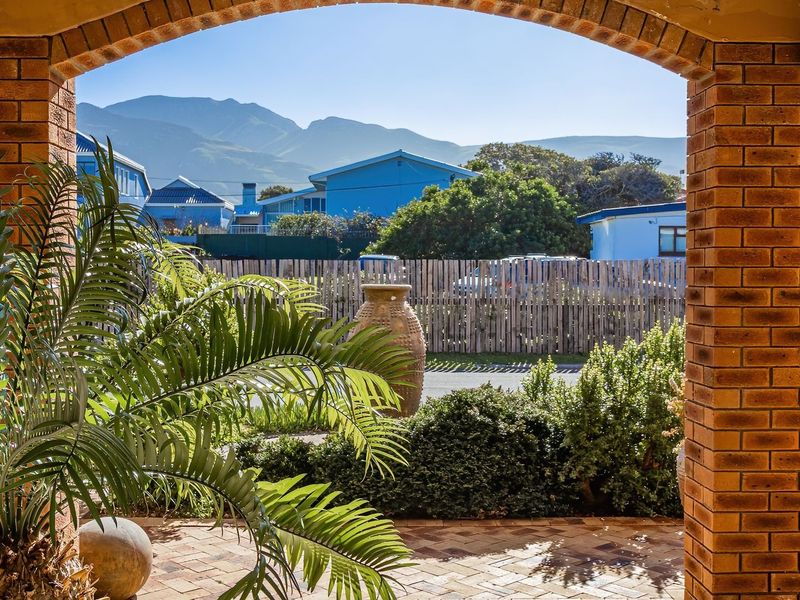 A covered patio area featuring classic brick archways and brick paving, offering a pleasant outlook towards the surrounding neighborhood and mountain views.