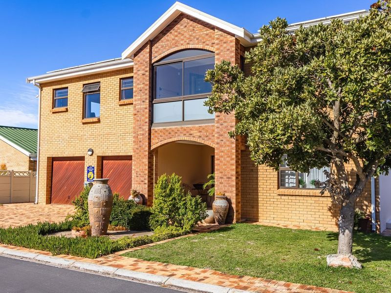 A well-maintained double-story brick house featuring a double garage, paved driveway, and an upper-level balcony.