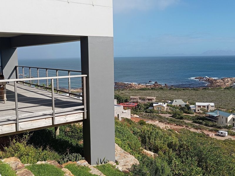 Spacious elevated timber deck featuring stainless steel cable railings, offering expansive coastal and ocean views.