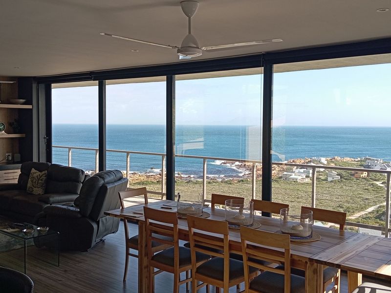 Spacious open-plan living and dining area featuring large sliding glass doors that offer expansive ocean views and access to a balcony.