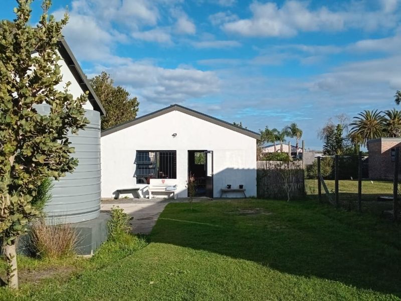 Rear view of the property featuring a lawn, concrete patio area, and a water tank adjacent to the main structure.
