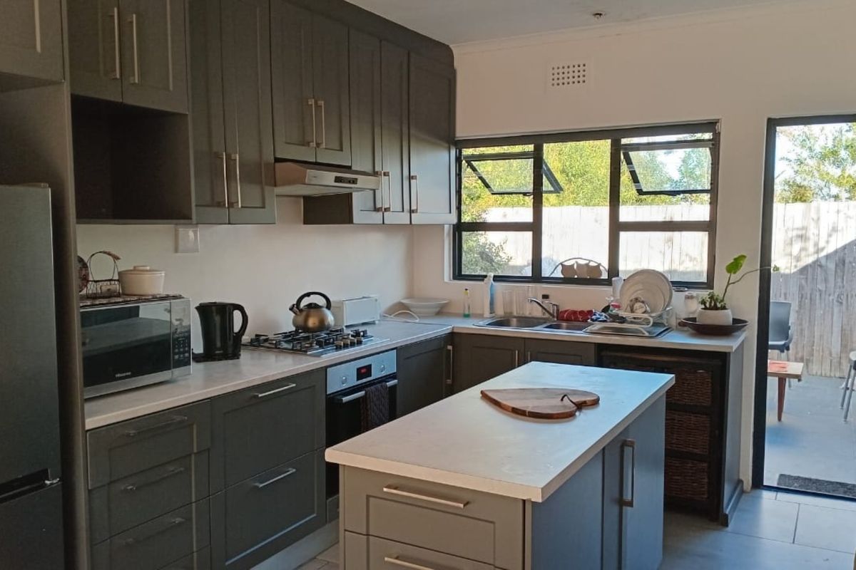 Modern kitchen featuring dark grey cabinetry, a central island, gas hob, built-in oven, and direct access to an outdoor patio area.