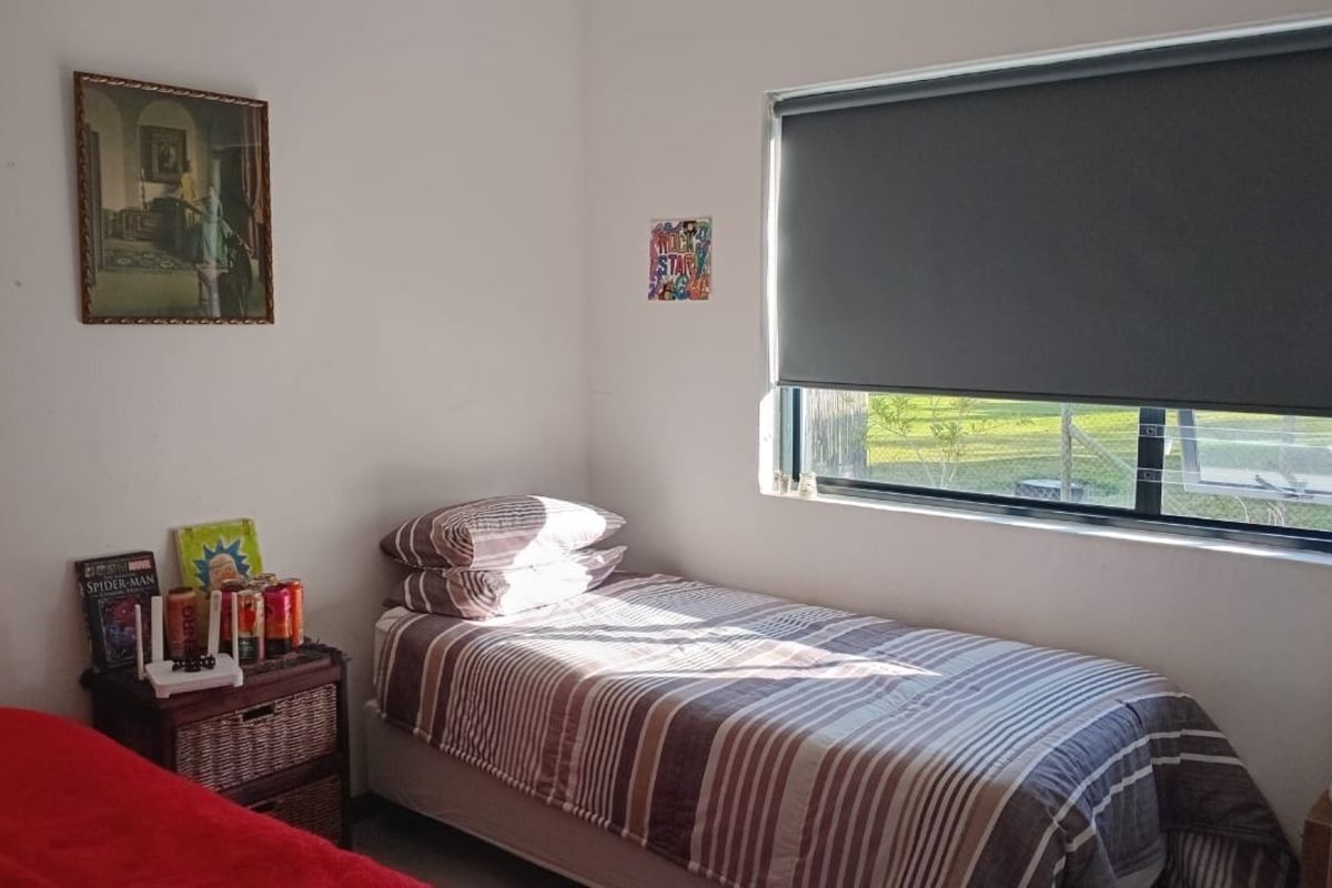 A functional bedroom featuring a window with a fitted roller blind, providing natural light and a simple layout.