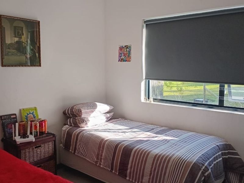 A functional bedroom featuring a window with a fitted roller blind, providing natural light and a simple layout.