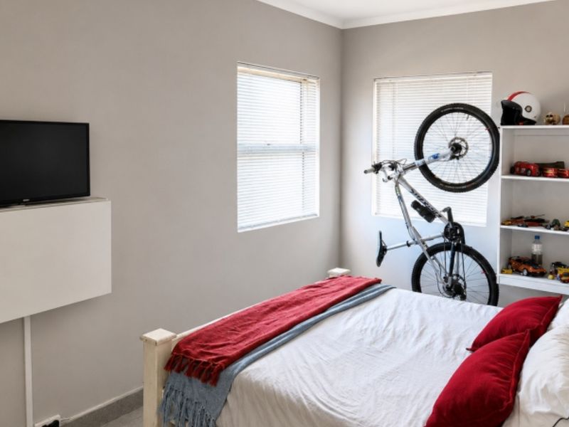 A well-maintained bedroom featuring neutral walls, built-in shelving, and venetian blinds, providing a functional and comfortable living space.