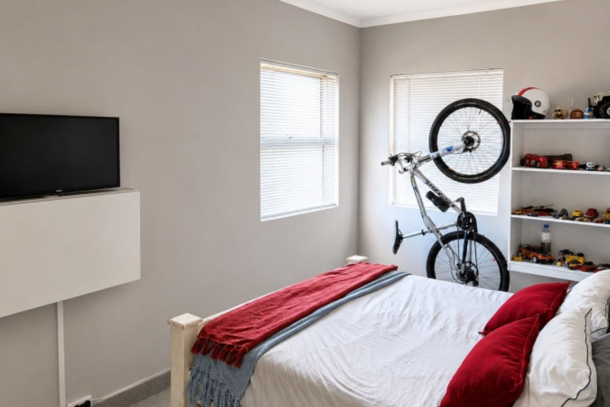 A well-maintained bedroom featuring neutral walls, built-in shelving, and venetian blinds, providing a functional and comfortable living space.