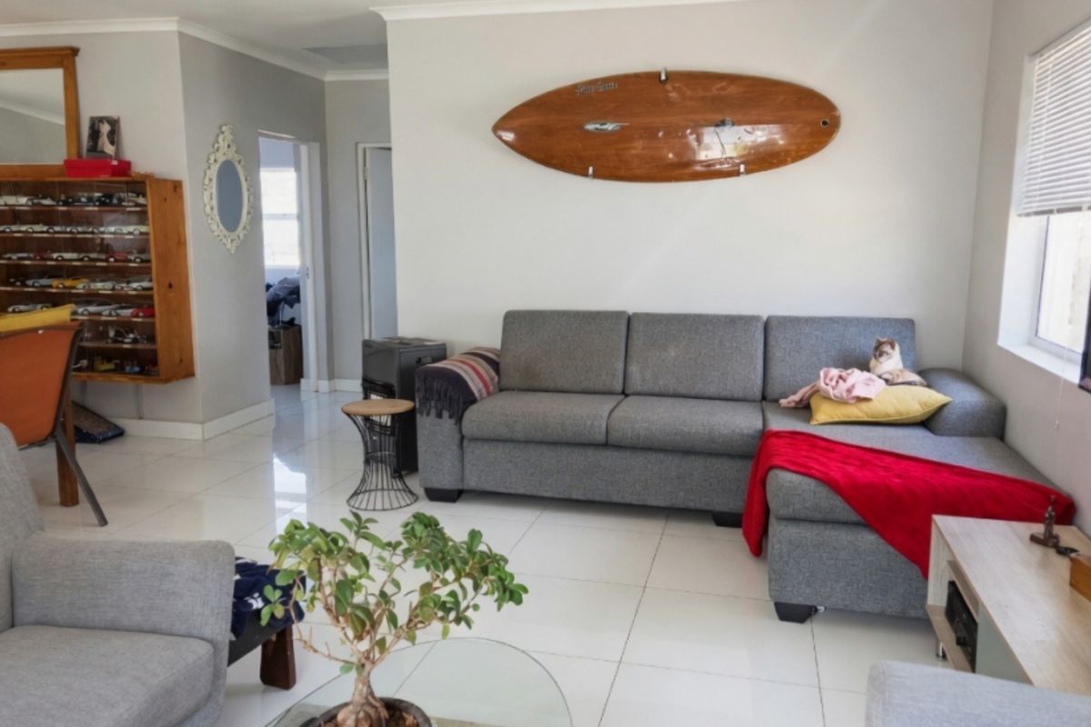 A bright living room featuring neutral tiled flooring, clean wall finishes, and natural light through a side window.