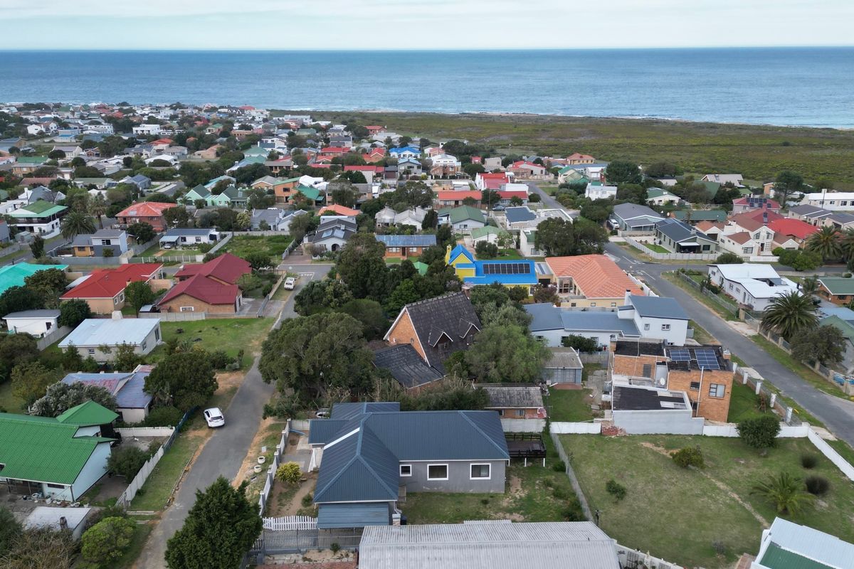 Aerial view of the residential property and surrounding coastal neighborhood, showcasing the roof structure, solar panel installation, and proximity to the ocean.