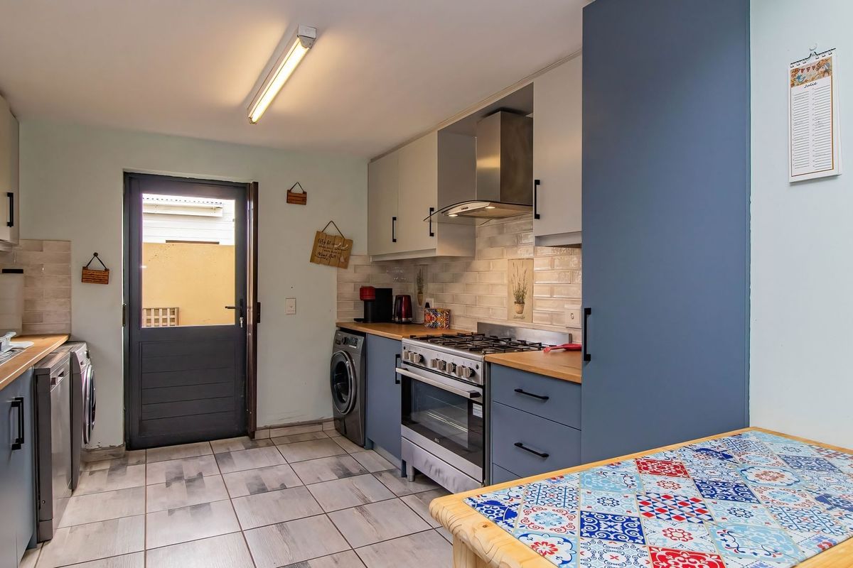 Functional kitchen featuring modern cabinetry, gas stove with extractor fan, subway tile backsplash, and direct access to the exterior.