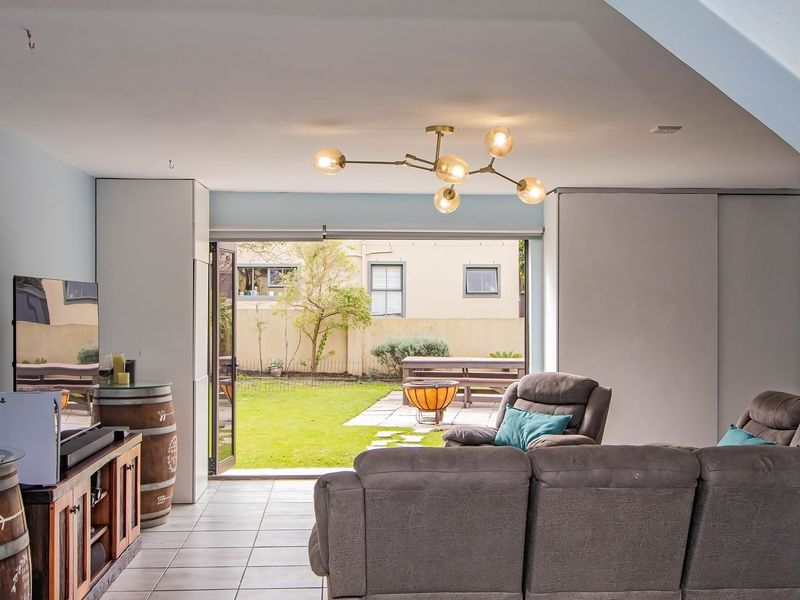 Spacious living area featuring tiled flooring, modern lighting, and large bi-fold doors that open directly onto the rear garden patio.