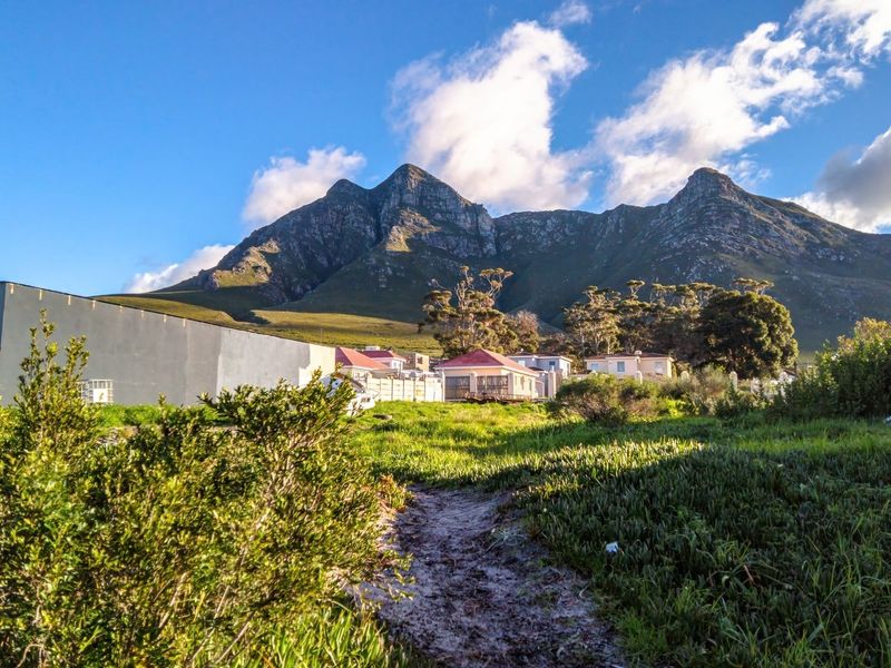 A scenic view of the mountain range overlooking the vacant residential land with natural vegetation and surrounding neighborhood structures.