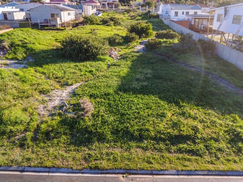 An elevated aerial view of a vacant residential plot featuring natural vegetation and surrounding boundary fencing in a developed neighborhood.