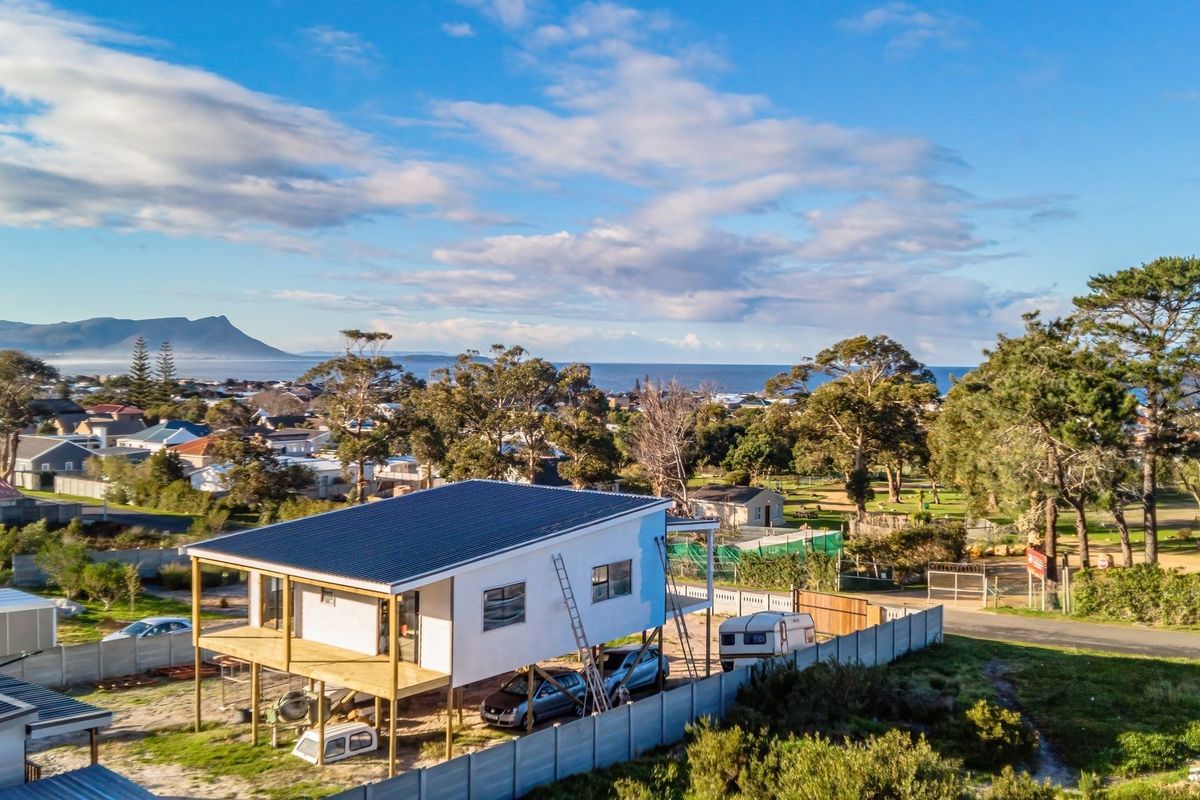 Aerial view of an elevated residential property under construction, featuring a timber deck and scenic coastal landscape views.