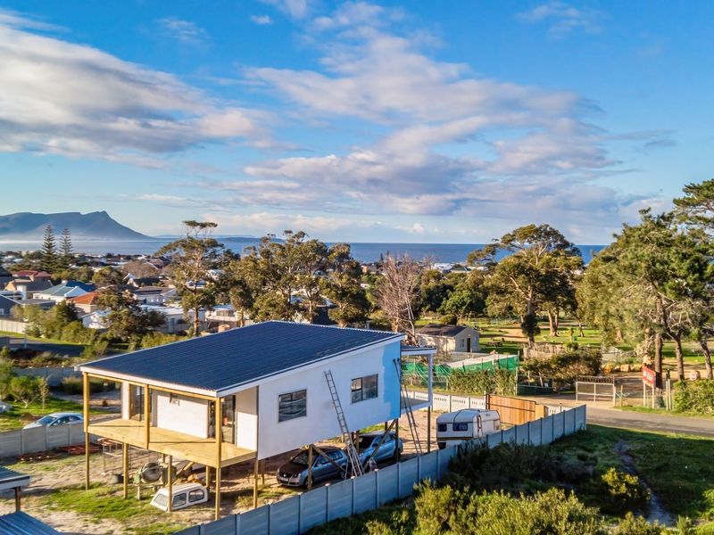 Aerial view of an elevated residential property under construction, featuring a timber deck and scenic coastal landscape views.