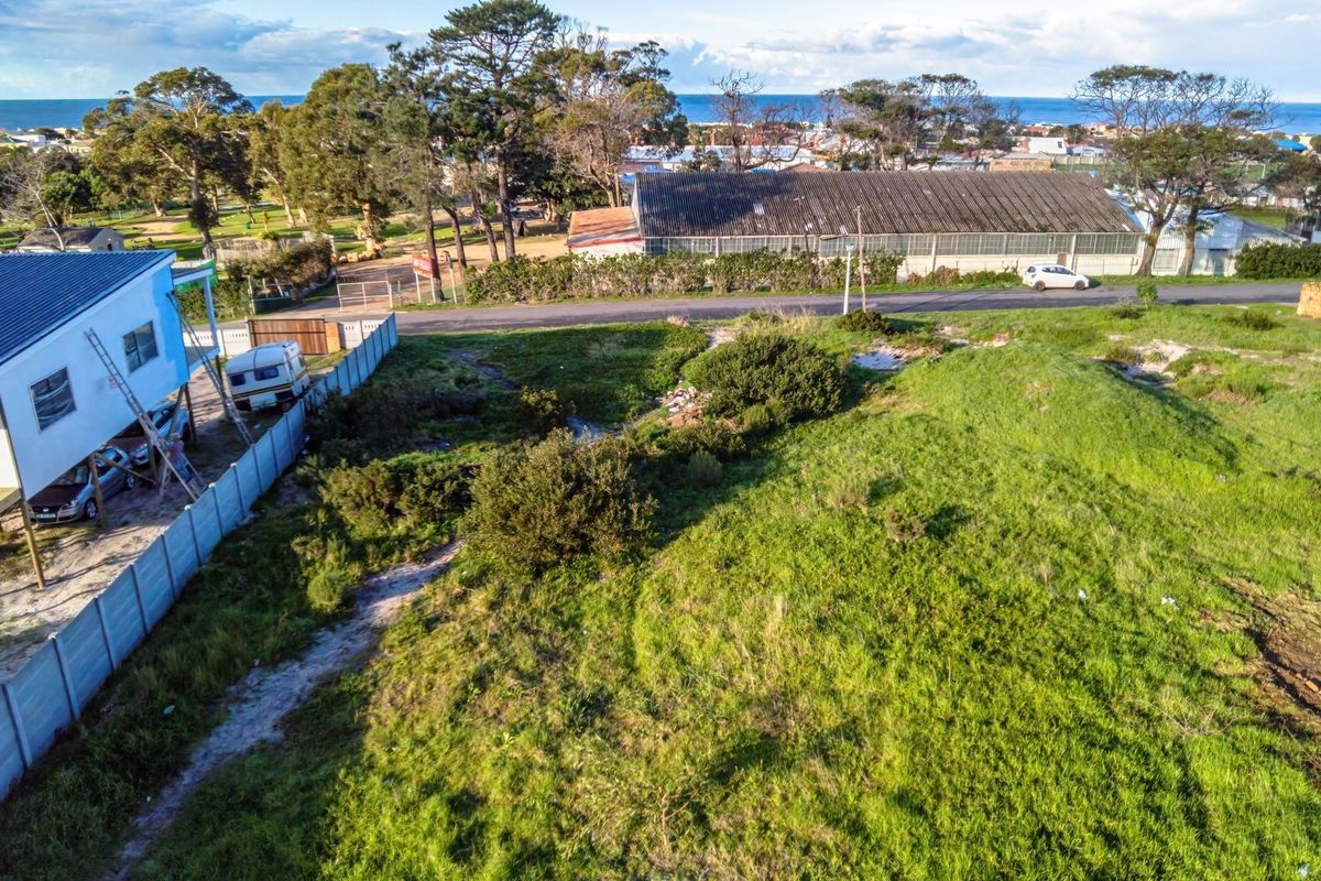 Aerial view of a vacant residential plot featuring natural grassland, perimeter fencing, and proximity to the coastline.