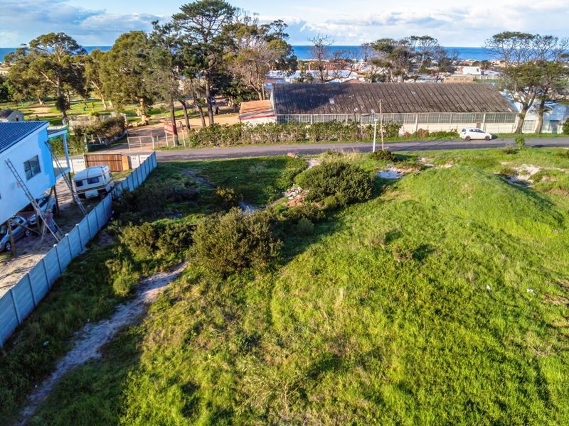 Aerial view of a vacant residential plot featuring natural grassland, perimeter fencing, and proximity to the coastline.