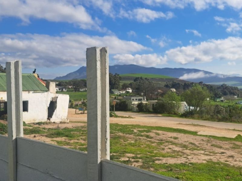 A scenic view overlooking a rural landscape with a mountain backdrop, featuring a precast concrete boundary wall in the foreground.