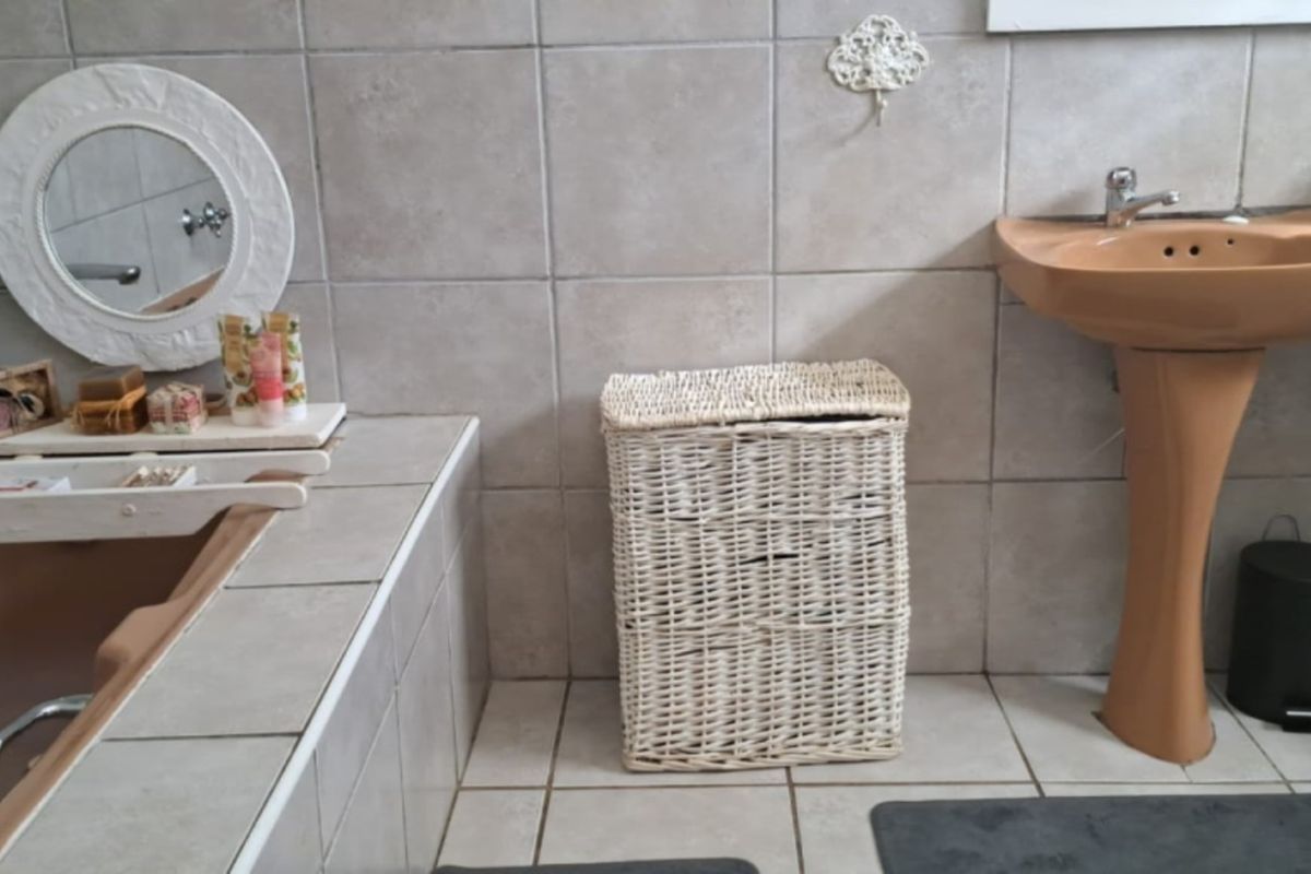 A functional bathroom featuring a pedestal basin, built-in bathtub, and neutral ceramic wall and floor tiling.