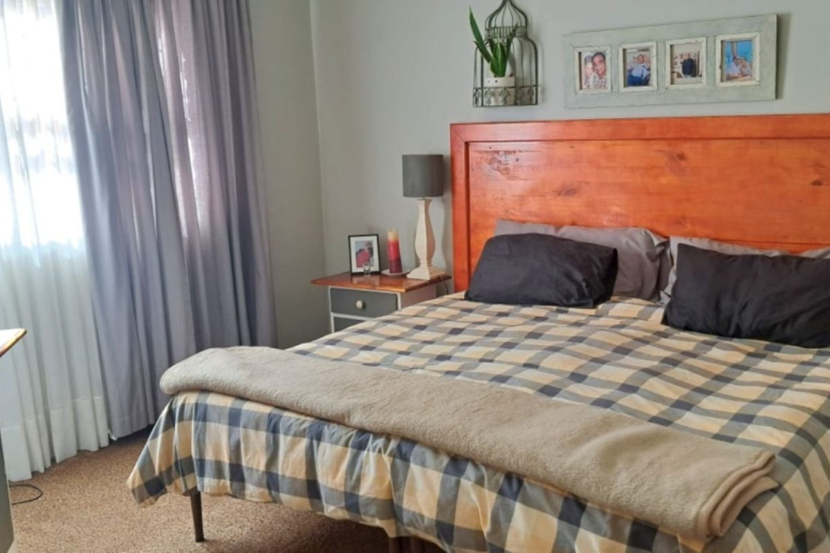 A functional bedroom featuring carpeted flooring and neutral wall finishes, providing a comfortable and well-lit sleeping space.