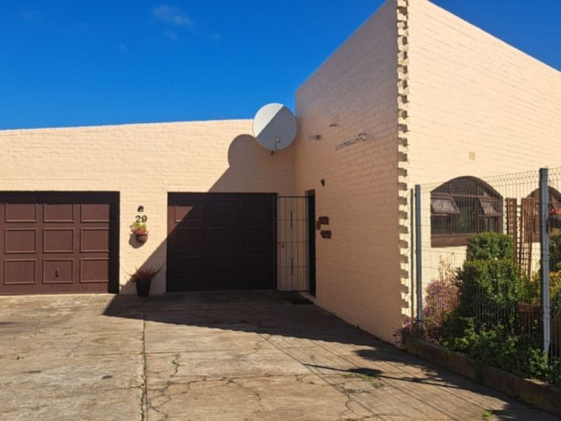Front exterior view of a residential property featuring a double garage, brick facade, and a concrete driveway with established garden borders.