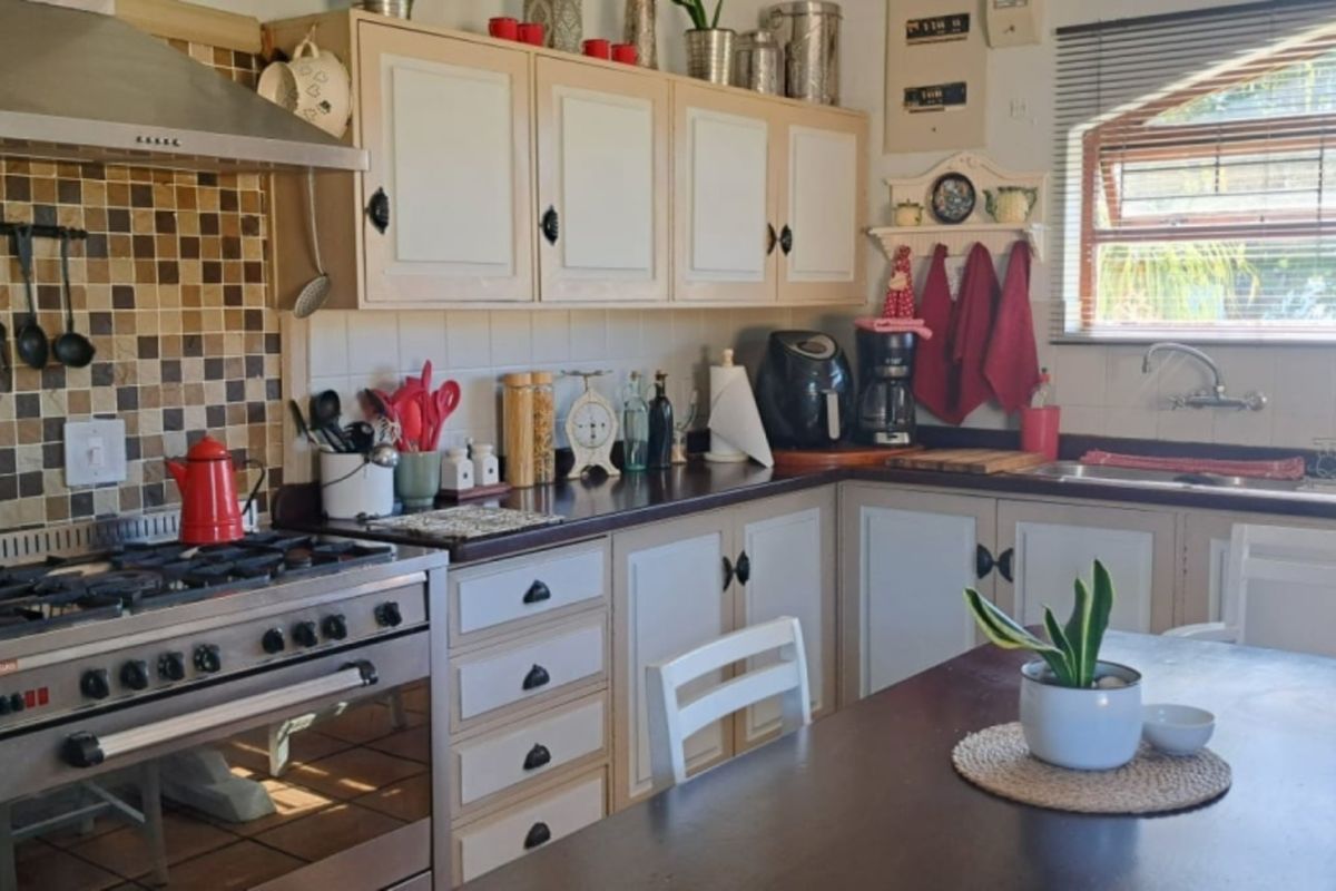 A functional kitchen featuring a gas stove, extractor fan, tiled backsplash, and ample built-in cabinetry with laminate countertops.