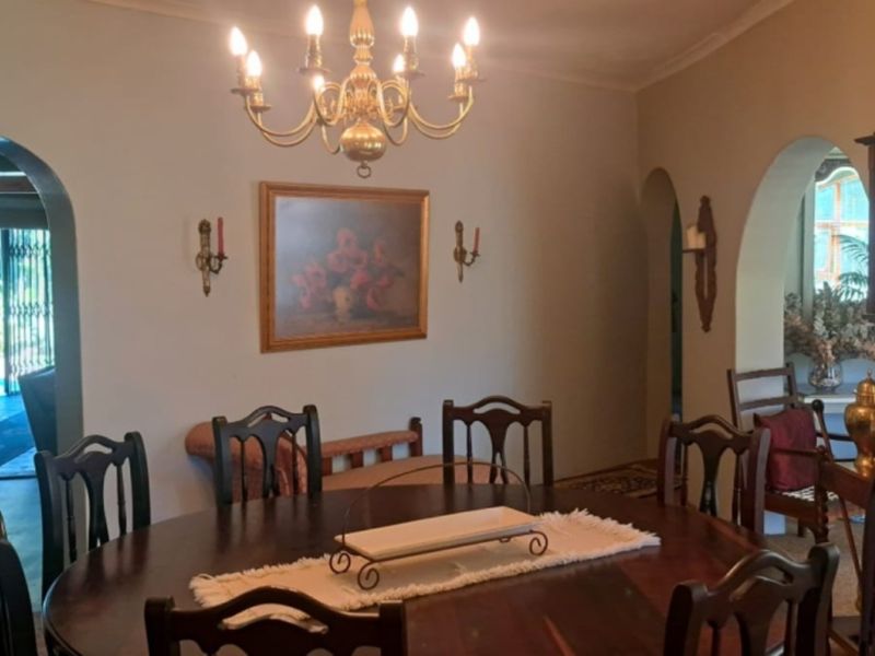 A traditional dining room featuring distinctive arched doorways, a classic chandelier, and wall sconces, creating a formal and connected living space.