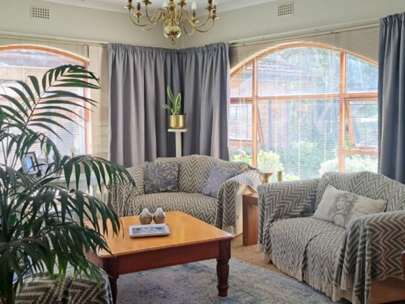 A comfortable living room featuring large arched windows that provide ample natural light and views of the garden.