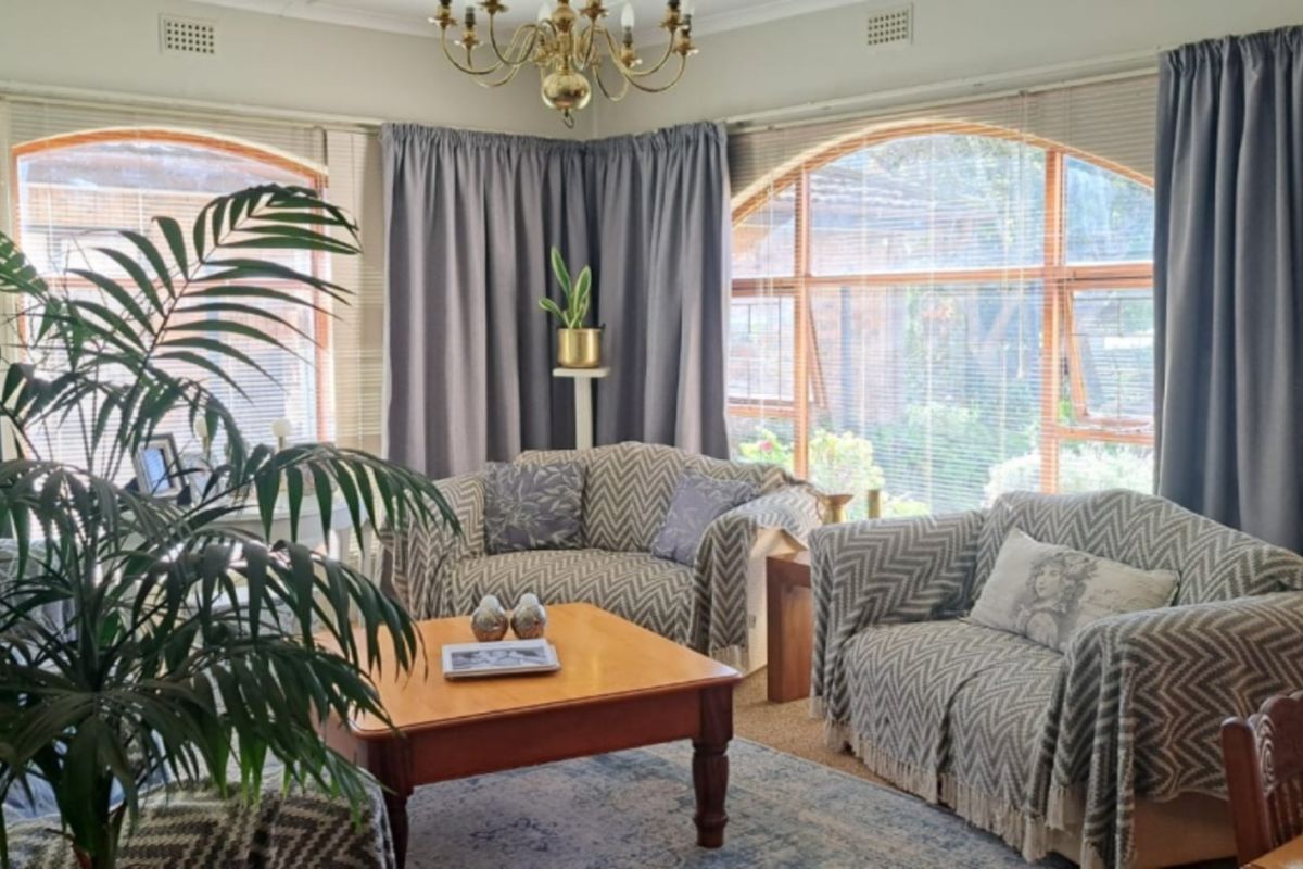 A comfortable living room featuring large arched windows that provide ample natural light and views of the garden.