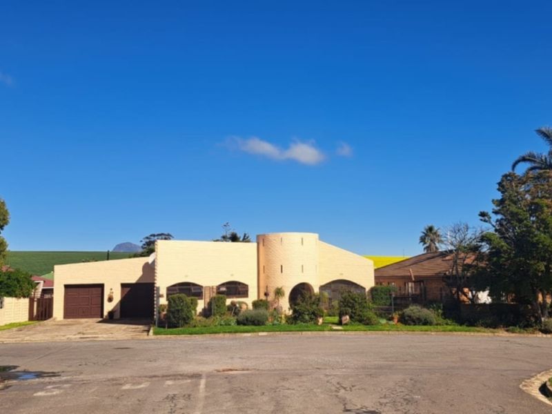 Front view of a single-story residential house featuring a distinctive arched entrance, brick exterior, and an attached double garage.