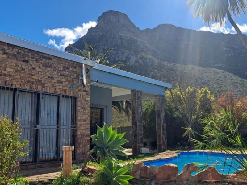 Rear exterior view featuring a swimming pool, covered patio area, and brick facade with mountain views.