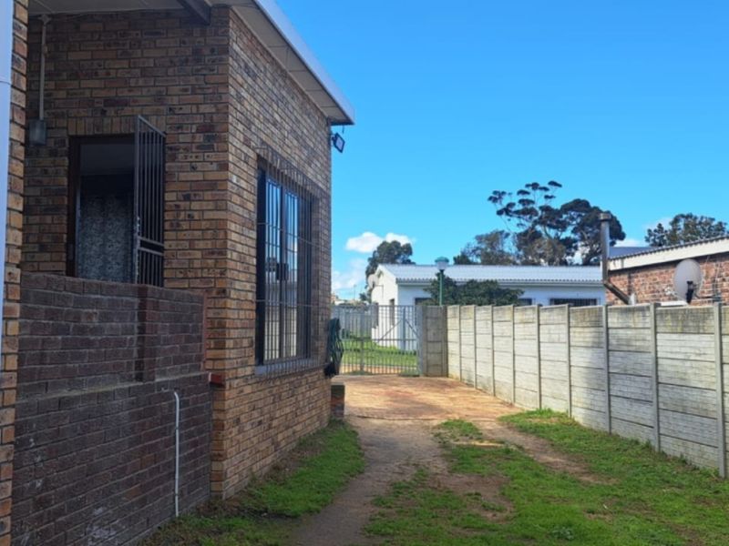 Rear exterior view of the property featuring face brick walls, security bars, a timber pergola, and a precast concrete boundary wall.