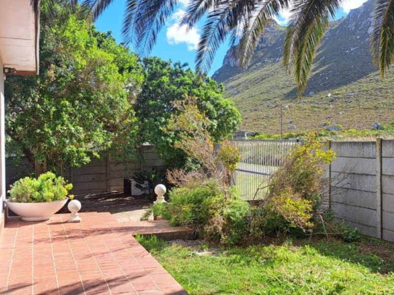 A rear garden area featuring a tiled patio, precast concrete boundary wall, and mountain views, providing a private outdoor space.