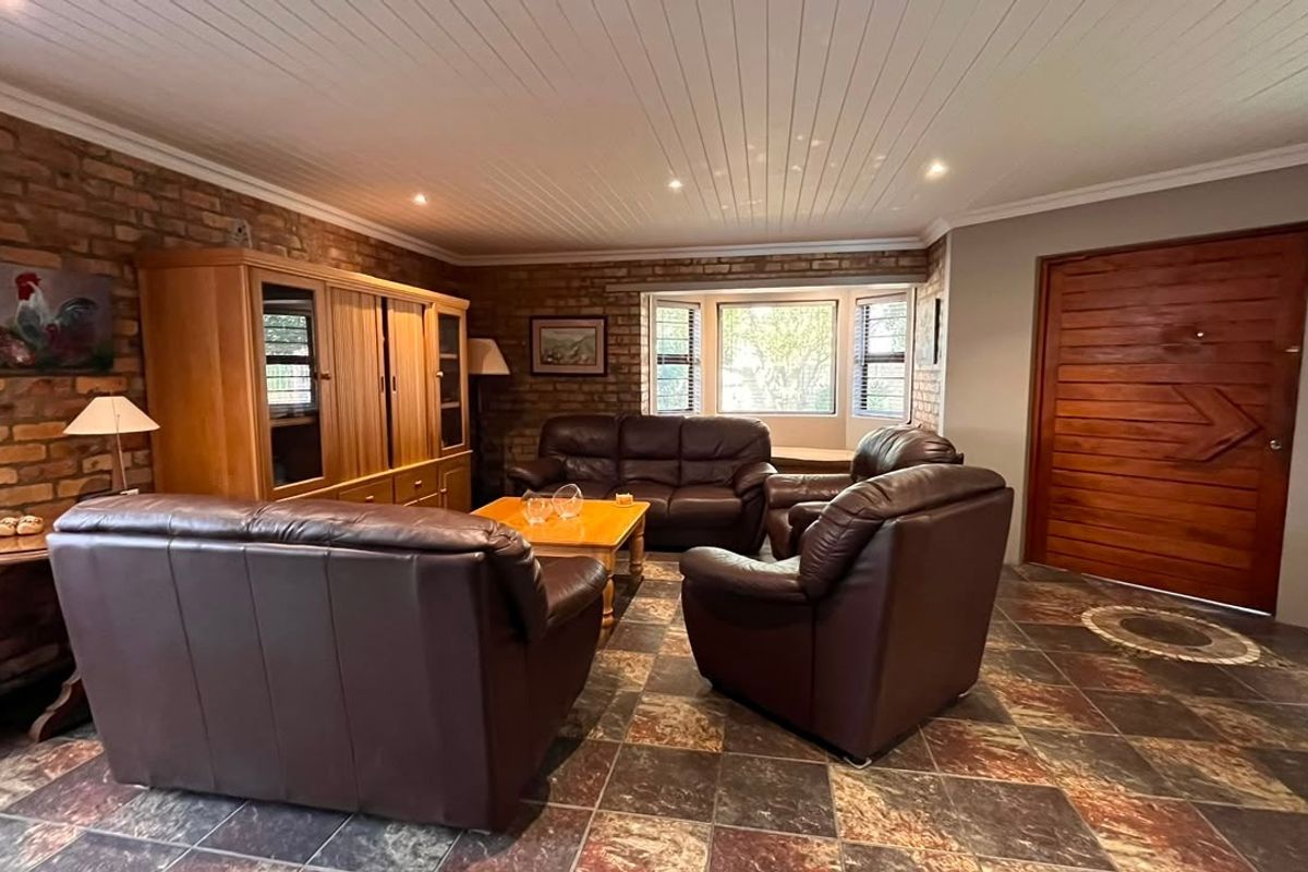 Spacious living room featuring exposed brick walls, timber panelled ceiling, tiled flooring, and a bay window, providing a warm and rustic atmosphere.