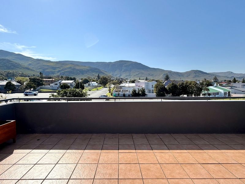 Spacious balcony featuring tiled flooring and a metal balustrade, offering expansive views of the surrounding neighborhood and mountain range.