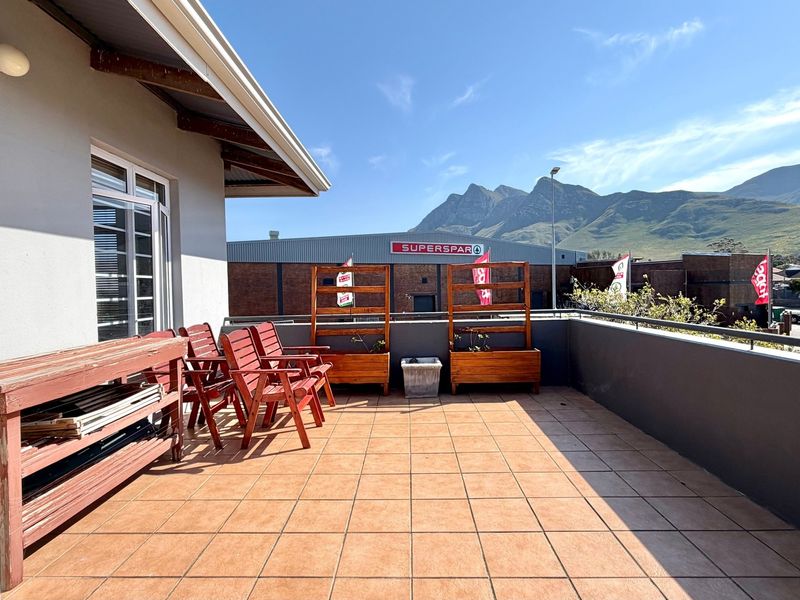 Spacious outdoor balcony featuring tiled flooring and a metal balustrade, offering mountain views and direct access to the interior living space.