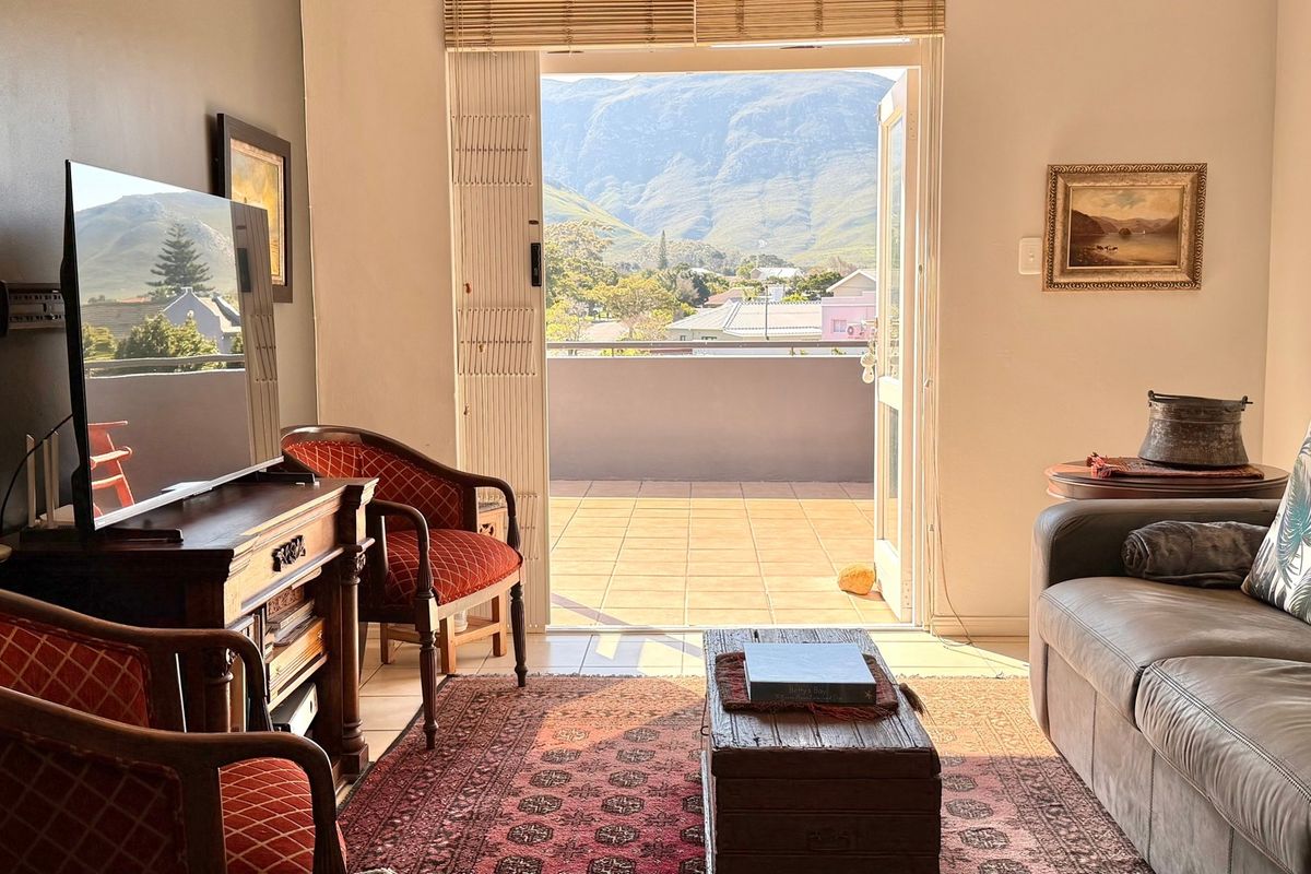 A comfortable living room featuring direct access to a tiled balcony with scenic mountain views through double glass doors.