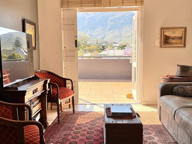 A comfortable living room featuring direct access to a tiled balcony with scenic mountain views through double glass doors.