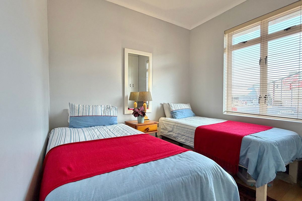 A functional bedroom featuring neutral wall finishes, coving, and a large window fitted with venetian blinds.