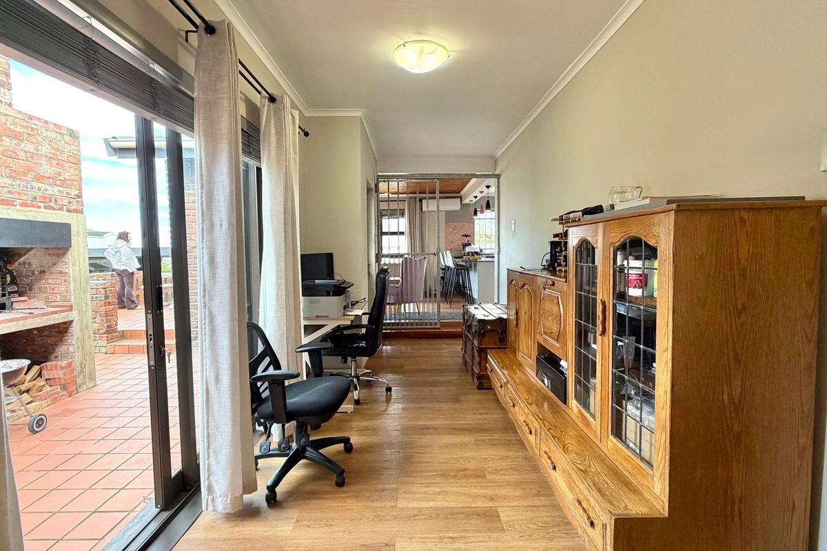 A bright living area featuring laminate flooring and large sliding glass doors that provide seamless access to the outdoor patio and brick fireplace.