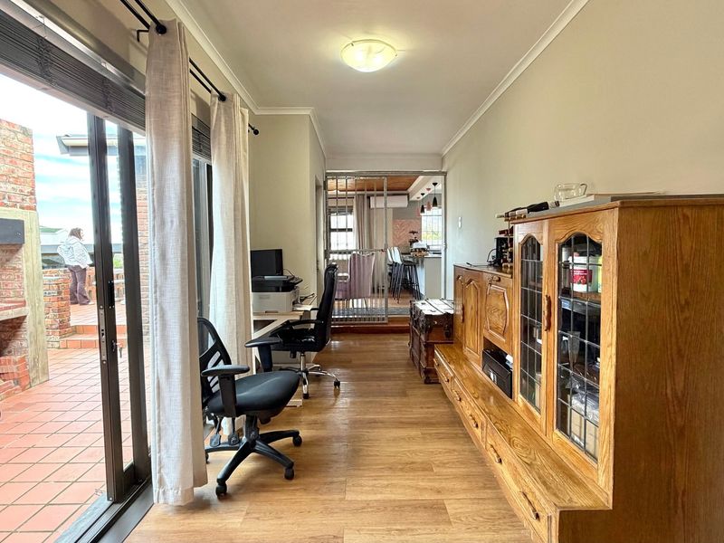 A bright living area featuring laminate flooring and large sliding glass doors that provide seamless access to the outdoor patio and brick fireplace.