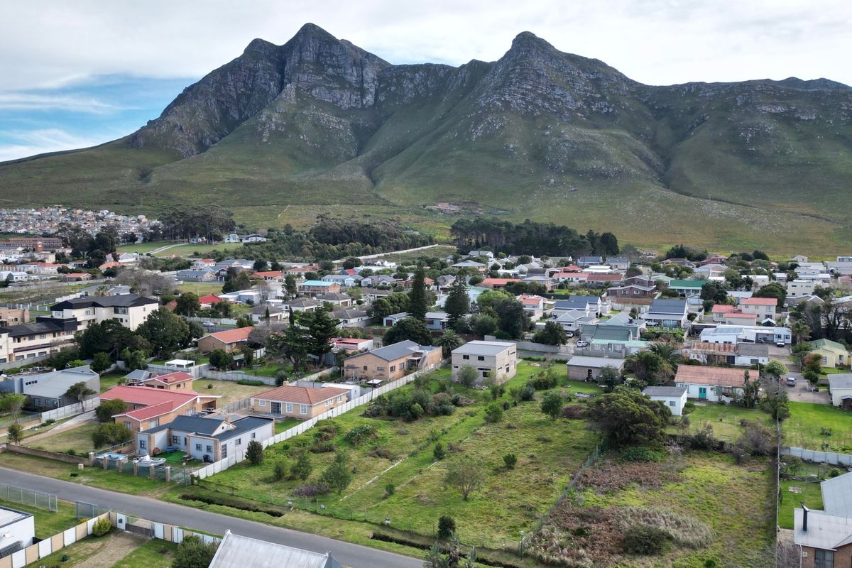 Aerial view of a residential neighborhood featuring a vacant plot of land with a scenic mountain backdrop.