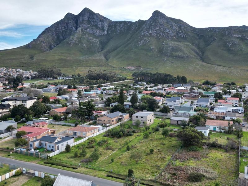 Aerial view of a residential neighborhood featuring a vacant plot of land with a scenic mountain backdrop.