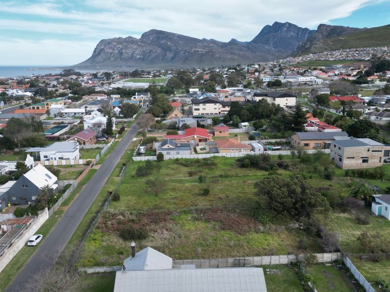 Aerial view of a vacant residential plot situated in a developed neighborhood with mountain and coastal views.